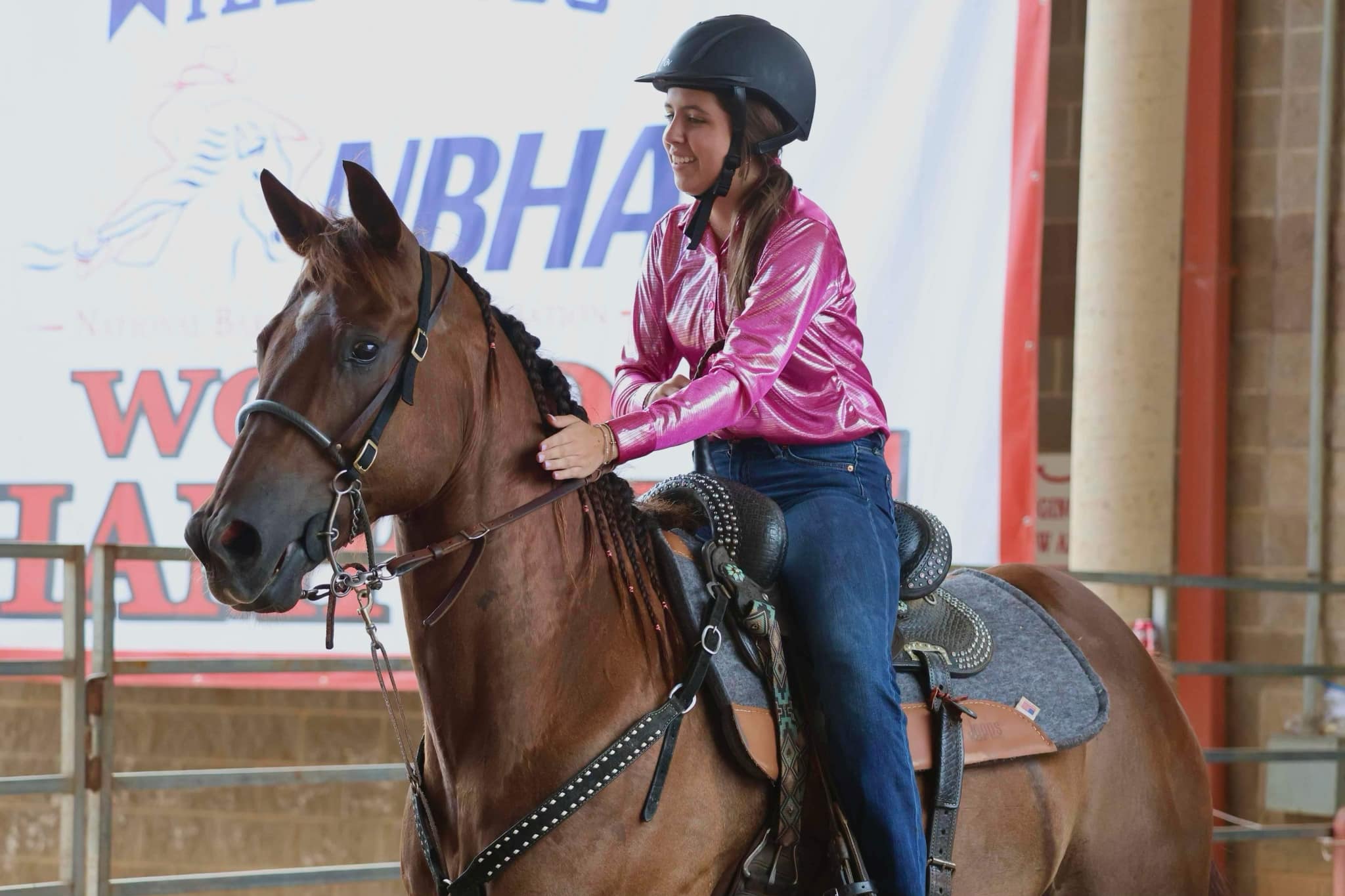 Girl on brown horse at a barrel racing competition, wearing a hot pink shirt by The Ranch.